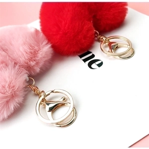 Cute pink and red heart plush keychains with golden rings on a minimalist card