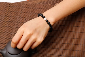 Detail of matte black and white turquoise beaded bracelet worn in a Zen tea setting
