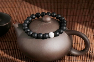 Macro detail of 8mm matte black beads and white turquoise on a vintage teapot