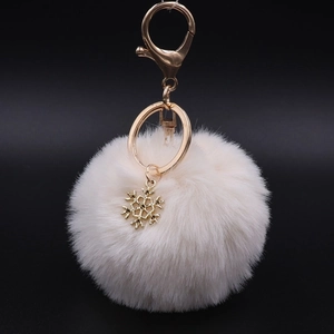 Detailed view of plush snowflake keychain with cream faux fur and golden alloy lobster clasp