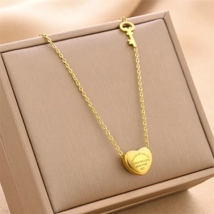 Gold titanium steel heart necklace with key pendant on beige jewelry display box