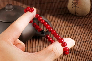 Detail of red turquoise beads bracelet with Zen stone and bamboo mat background