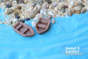 Macro shot of miniature resin boats with wood grain texture on blue sand beach background
