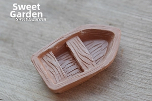 Close-up of a miniature resin boat model with detailed wood grain texture for terrariums