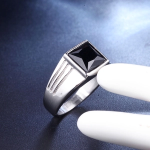Detail view of men's silver stainless steel ring with square black gemstone and stripes