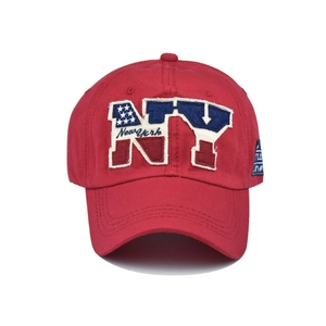 Detailed close-up of NY embroidery and American flag motifs on a red cotton baseball cap