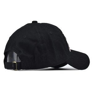Detail of adjustable cotton strap and brass metal buckle on a black baseball cap
