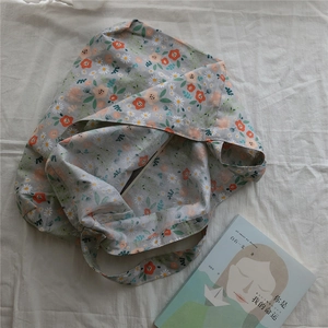 Floral cotton shoulder bag with daisy pattern flat lay on white sheet and book