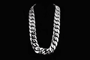 Macro view of a 31mm thick silver stainless steel Cuban link chain for men on black background