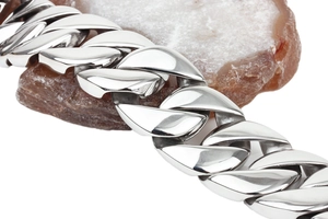 Macro detail of silver stainless steel Cuban link chain resting on a red agate stone