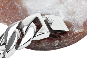 Macro shot of silver stainless steel Cuban link chain over a natural agate stone