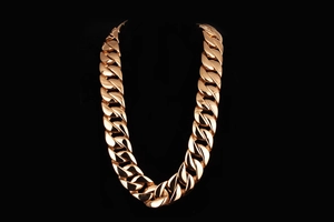 Macro detail of thick rose gold Cuban link necklace with polished heavy steel chain
