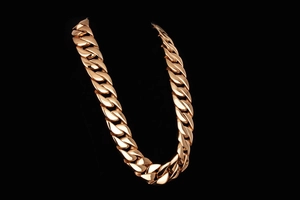 Macro shot of thick gold-plated Cuban link chain for men on a black background