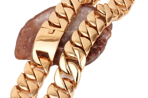 Close-up of a chunky gold-plated Cuban link necklace wrapped on a red agate stone