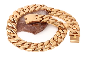 Detailed close-up of a chunky golden Cuban link chain resting on a natural brown stone