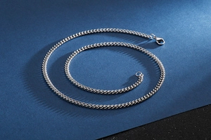 Macro view of polished silver stainless steel Cuban chain necklace with lobster clasp