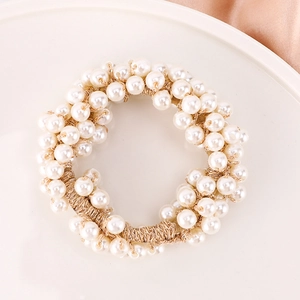 Close-up of elegant ivory faux pearls on a golden elastic hair tie for ponytails