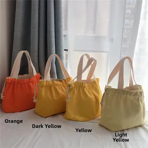 Detail of canvas drawstring tote bags in four gradient yellow shades with beige handles