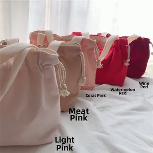 Five canvas drawstring bags in shades of pink and red with white woven handles