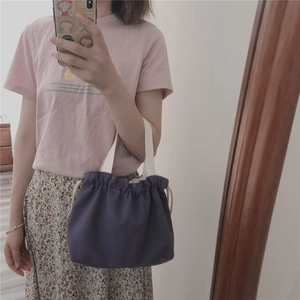 Detail view of purple canvas bucket bag with drawstring closure and cream handles