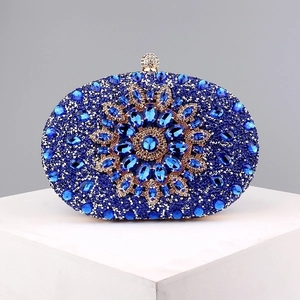 Close-up of blue floral rhinestone pattern and golden crystal clasp on luxury evening bag