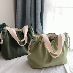 Detail of canvas drawstring handbags in green shades with thick cotton straps
