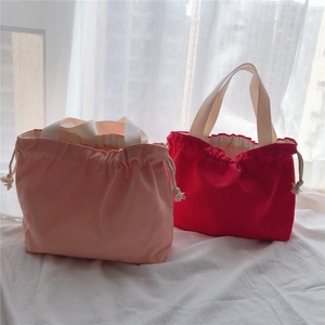 Detail of pink and red canvas drawstring tote bags with cotton ropes on white fabric