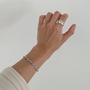 Detail of 925 sterling silver twisted chain bracelet and rings on model hand