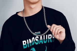 Close-up of a silver stainless steel cross chain necklace worn by a male model