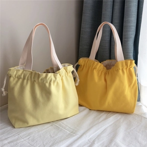 Detail of canvas tote bags in yellow shades with drawstring closure and texture