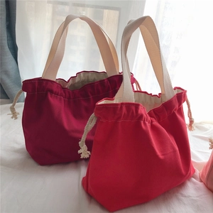 Detail of red drawstring canvas tote bags featuring thick fabric and white cotton handles
