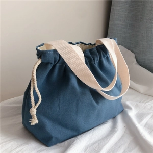 Detail of dark blue canvas drawstring tote bag with off-white cotton ribbon handles