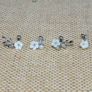 Detail of silver floral stud earrings featuring white pearls and zircon on mesh texture