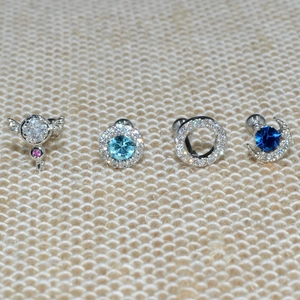 Detailed close-up of mixed geometric ear studs with zirconia and colorful gemstones