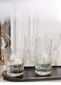 Macro detail of hand-painted daisy glass set with hammered texture and floral pattern