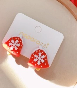 Close-up of red Christmas bell earrings with snowflake patterns on display card