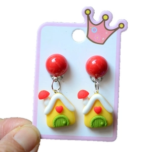 Detail of yellow house-shaped earrings with red mushroom and heart accents for Christmas