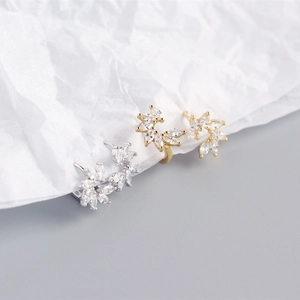 Macro shot of silver and gold leaf-shaped earrings with marquise cubic zirconia stones