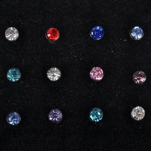 Detail of 12 colorful crystal stud nose pins on black velvet display tray