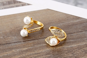 Close-up of gold titanium rings featuring faux pearls and sparkling leaf shaped rhinestones