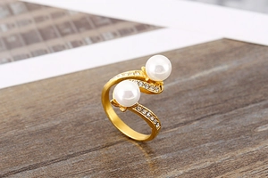 Macro shot of gold wave ring featuring elegant pearls and sparkling small diamonds