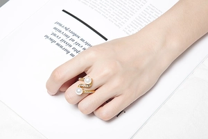 Detailed view of an elegant gold ring with pearls and pavé diamonds worn on a finger