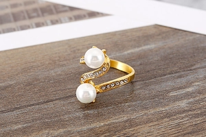 Macro detail of gold S-shaped ring featuring twin pearls and sparkling pavé rhinestones