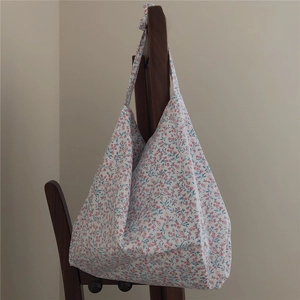 Detail of floral cotton tote bag with soft pleats hanging on a wooden chair