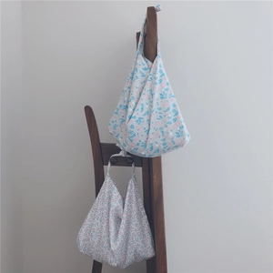 Close-up of floral cotton tote bags hanging on a wooden chair in a cozy home setting