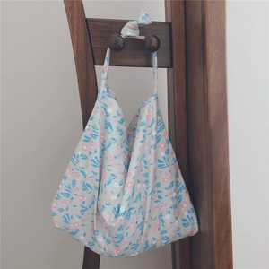 Detailed close-up of floral cotton handbag with knot handle detail on wooden rack