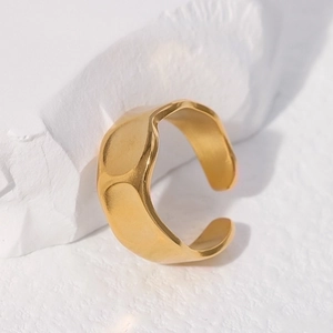 Irregular textured gold stainless steel open ring on a white stone background