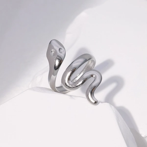 Macro detail of silver snake ring with spiral design on a minimalist stone pedestal