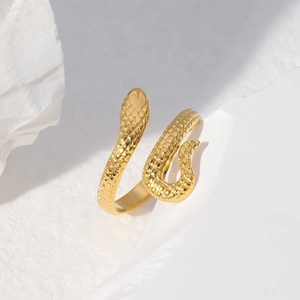Detailed view of adjustable golden snake ring with textured scales on white rock base