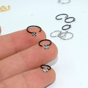 C-shaped black stainless steel nose rings with clear zircon stones shown on fingers